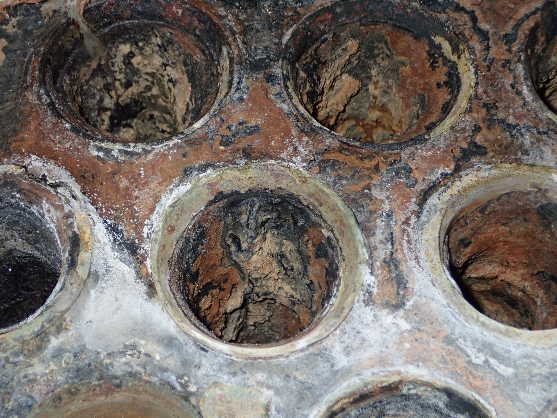Close-up of a heavily corroded tube sheet showing scale, pitting and degraded tube openings