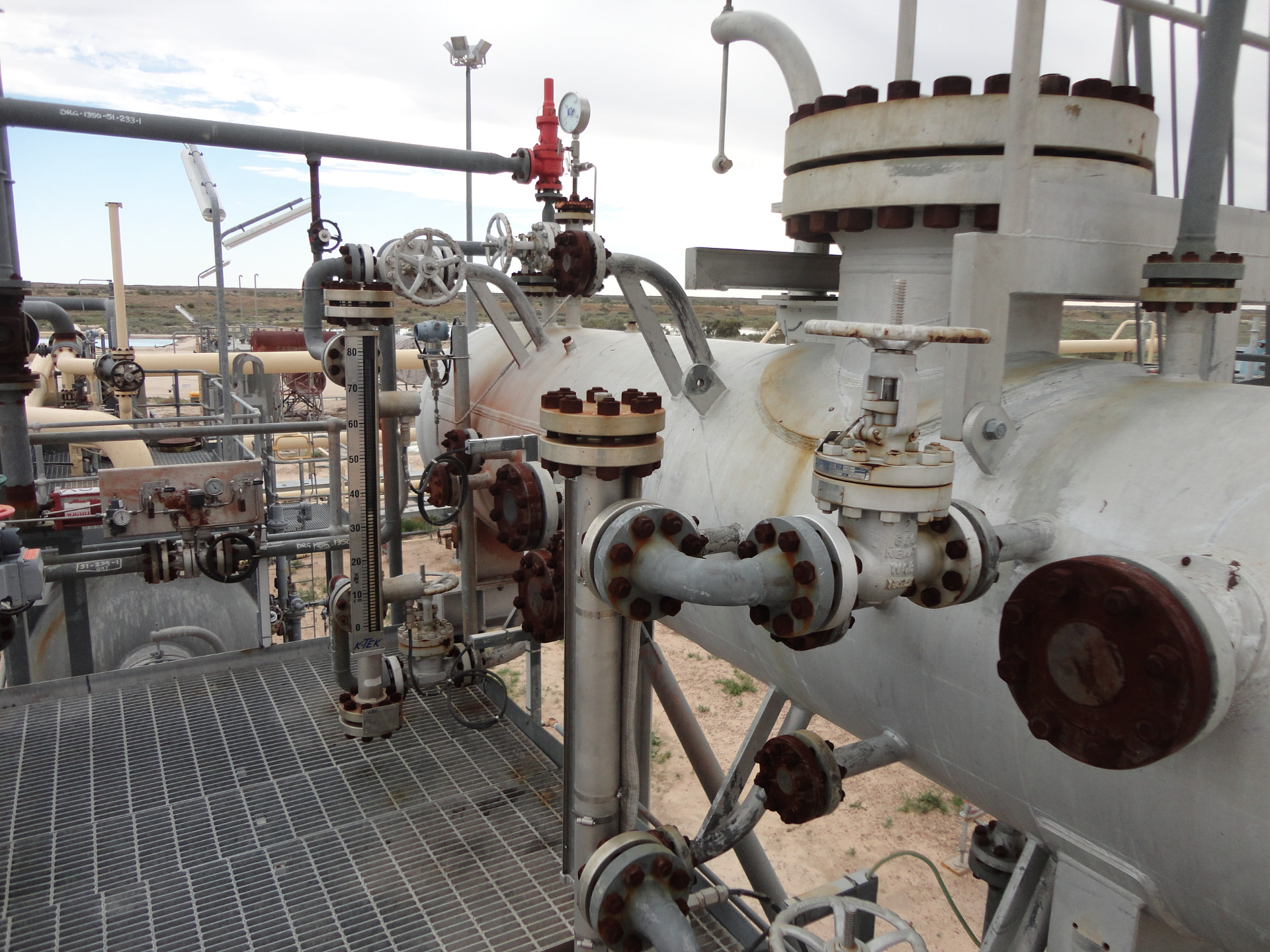 Outdoor pressure vessel and process piping with valves, flanges and gauges at an industrial facility