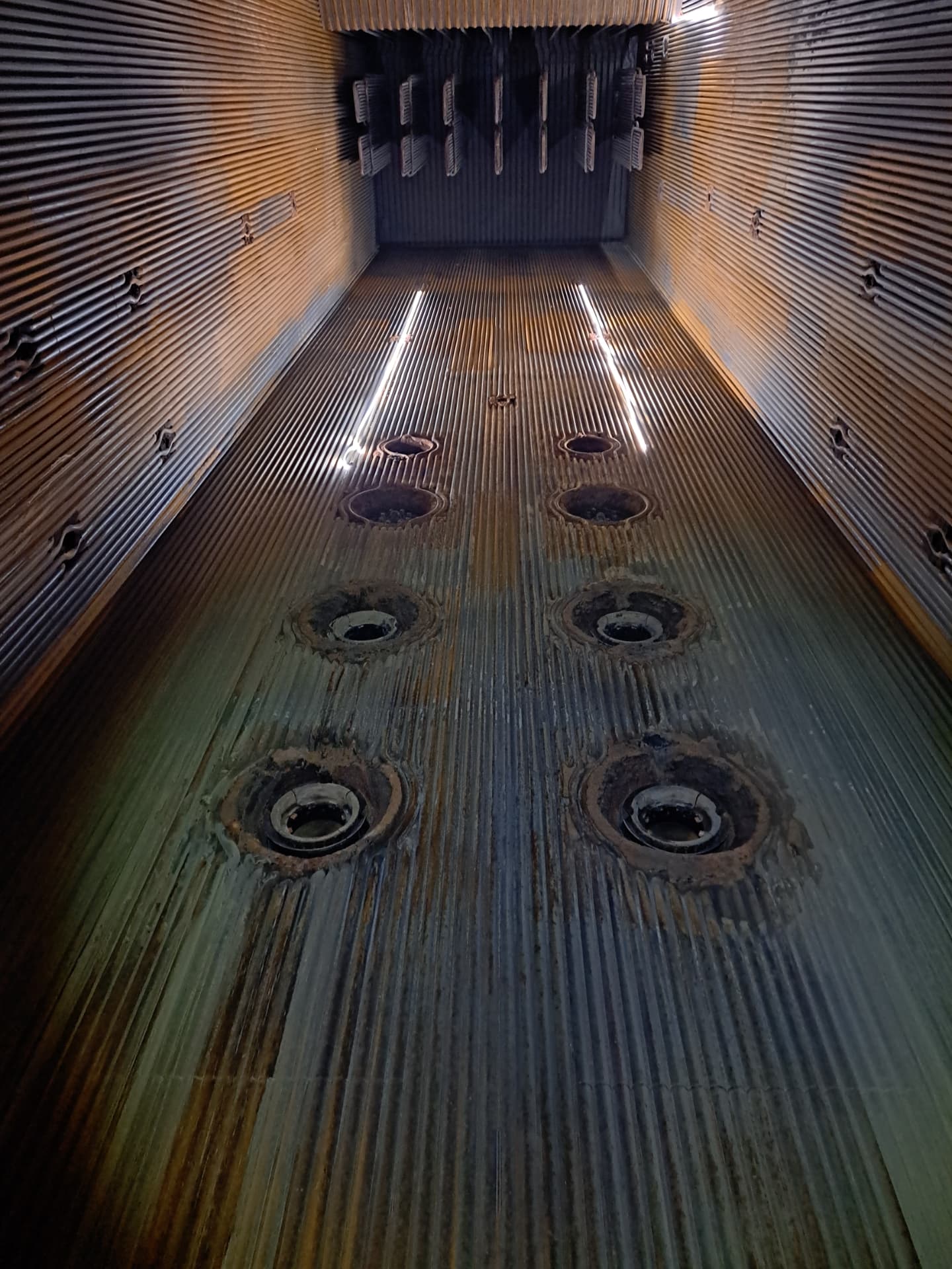 Internal view of a pressure vessel with tube penetrations and vertical ribbed walls